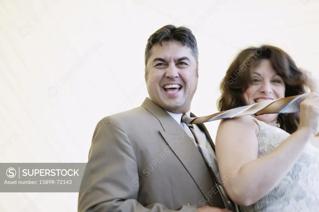 Hispanic woman pulling husband by tie
