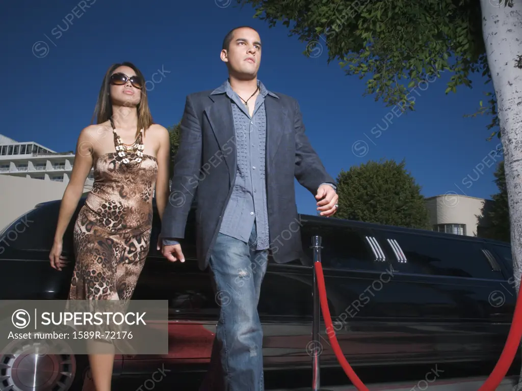 Multi-ethnic couple walking away from limousine