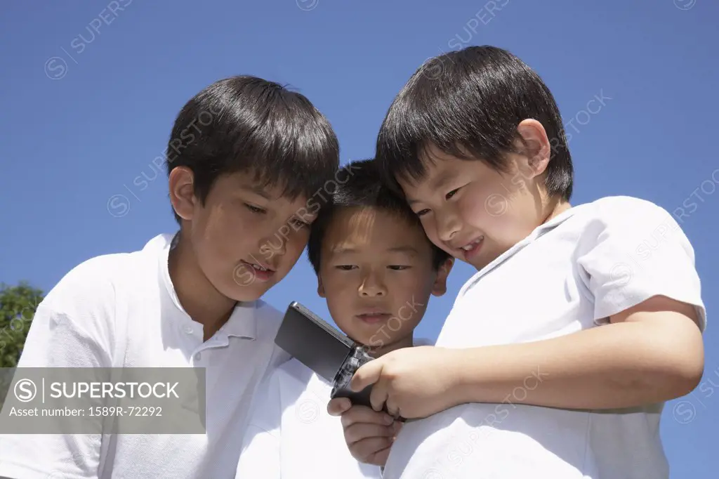 Multi-ethnic boys looking at cell phone
