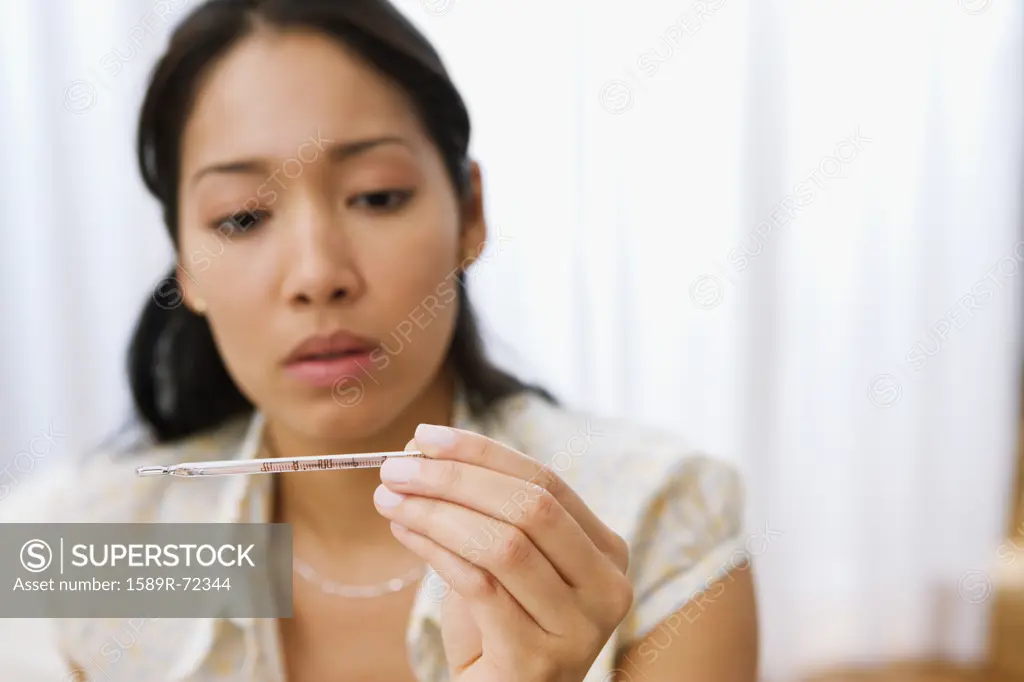Pacific Islander mother looking at thermometer