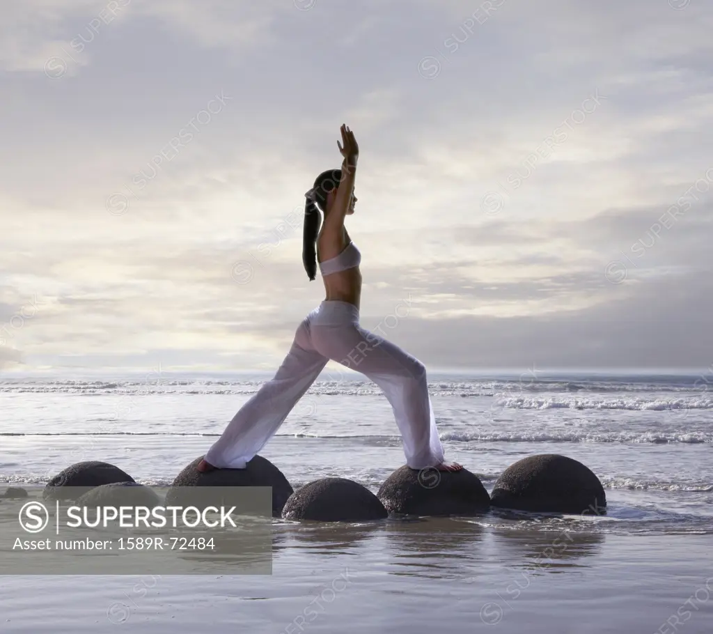 Pacific Islander woman practicing yoga at beach