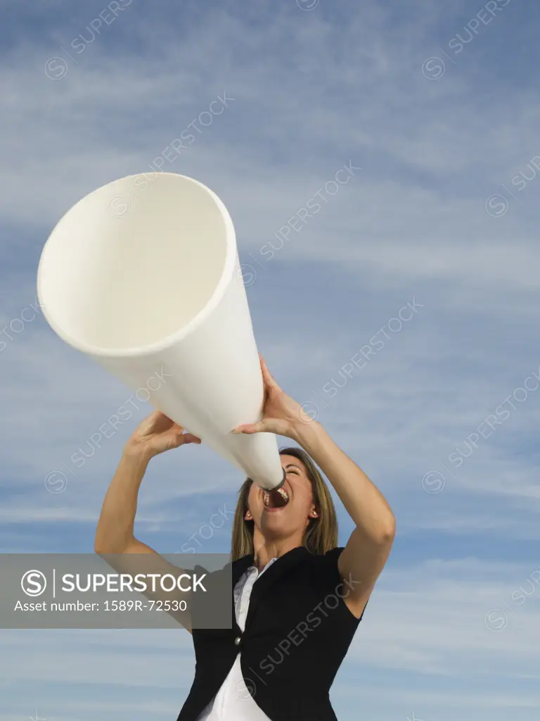 Hispanic businesswoman yelling into megaphone