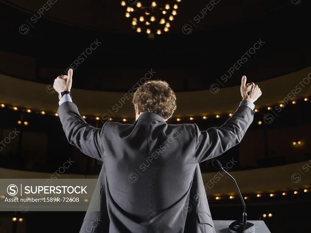 Businessman giving thumbs up on stage
