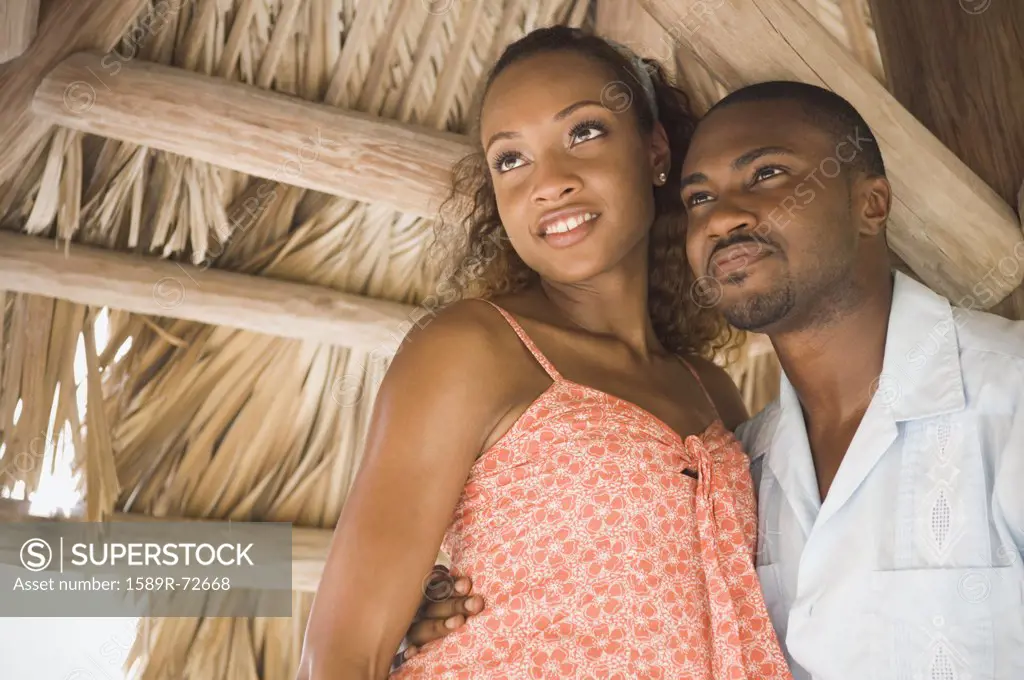 African American couple hugging in grass hut