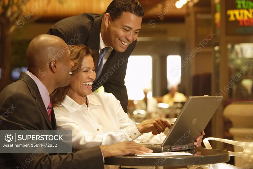 Multi-ethnic businesspeople laughing at laptop