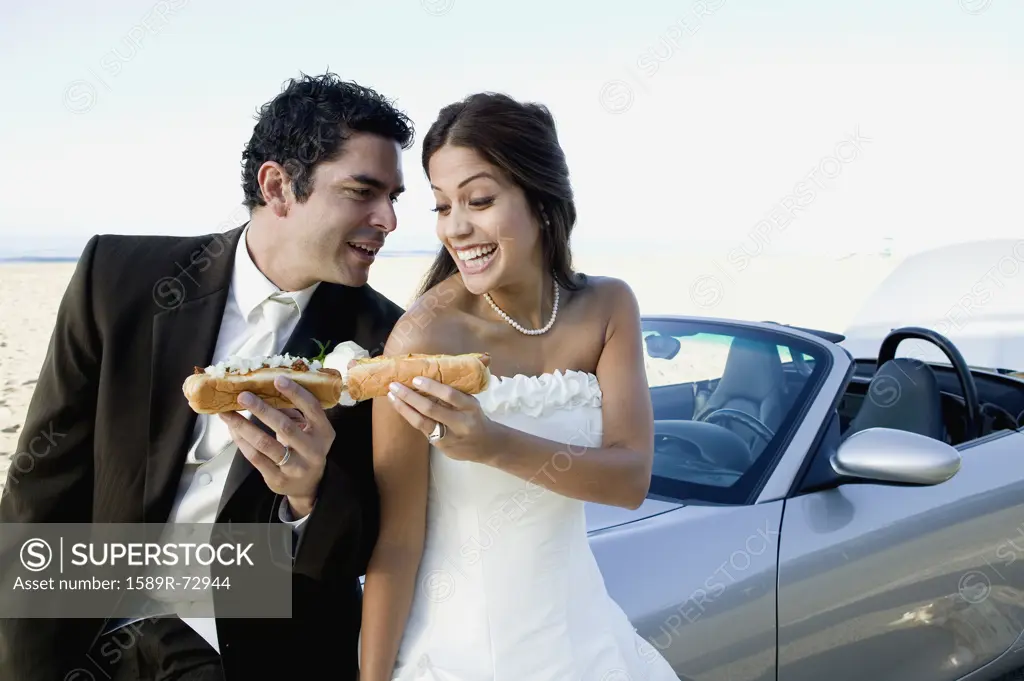Hispanic newlyweds eating hot dogs