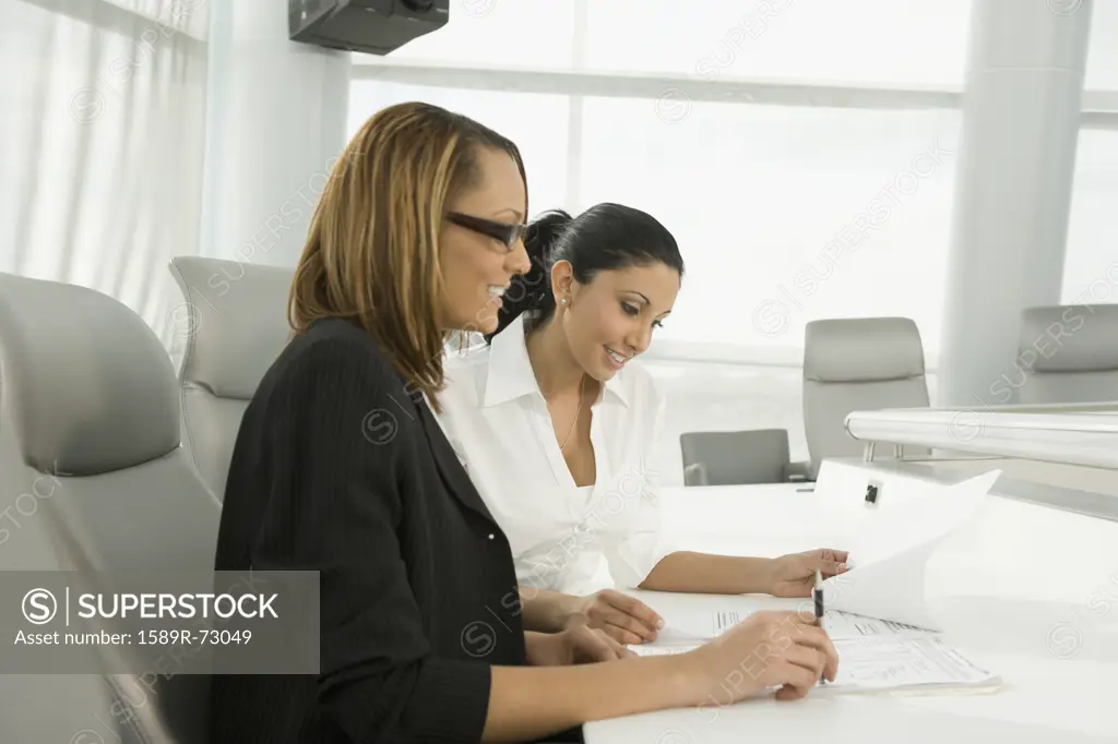 Multi-ethnic businesswomen reviewing paperwork in meeting