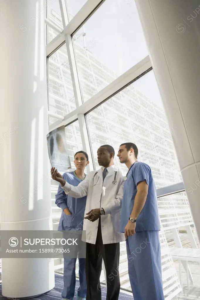 Multi-ethnic doctor and nurses reviewing x-ray by window