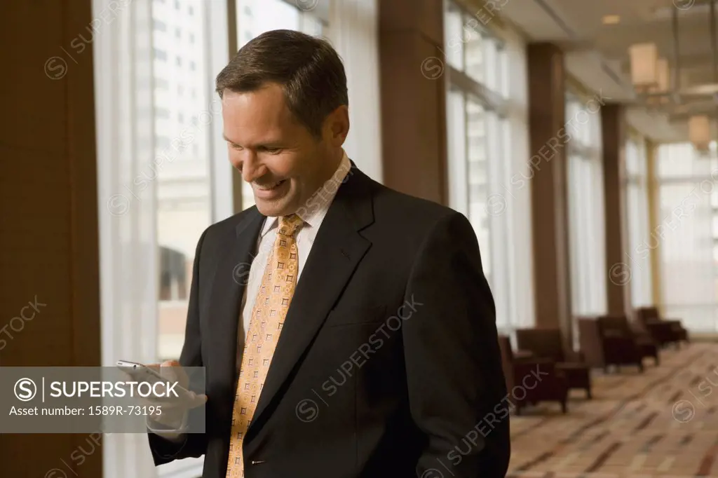 Businessman looking at cell phone in corridor