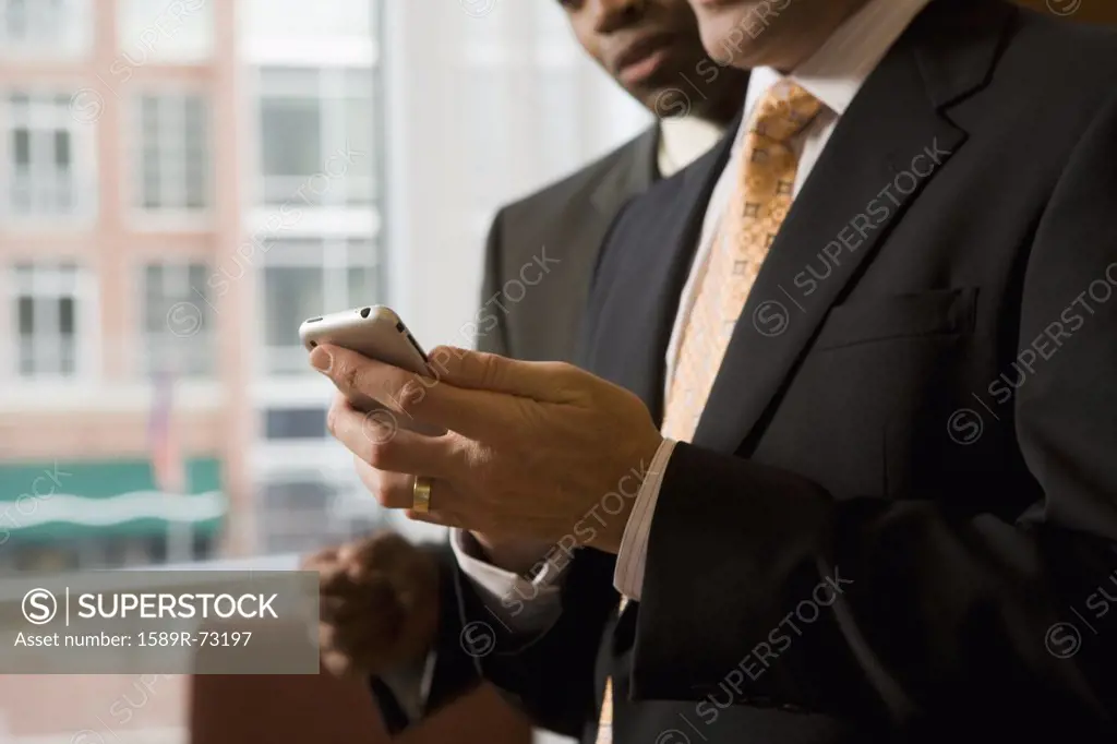 Multi-ethnic business people looking at cell phone