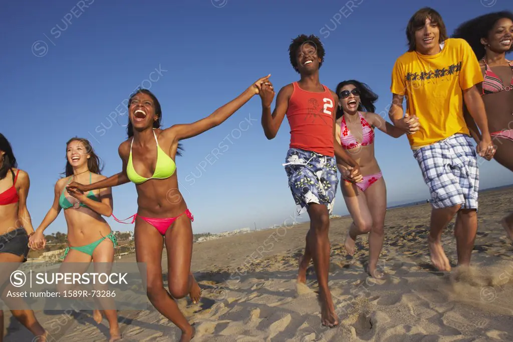 Multi-ethnic group of friends running on beach
