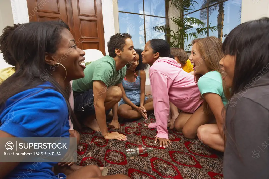 Multi-ethnic group of friends playing spin the bottle