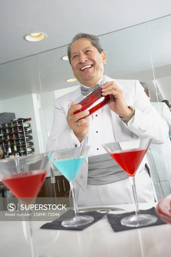 Hispanic host mixing martini cocktails at party