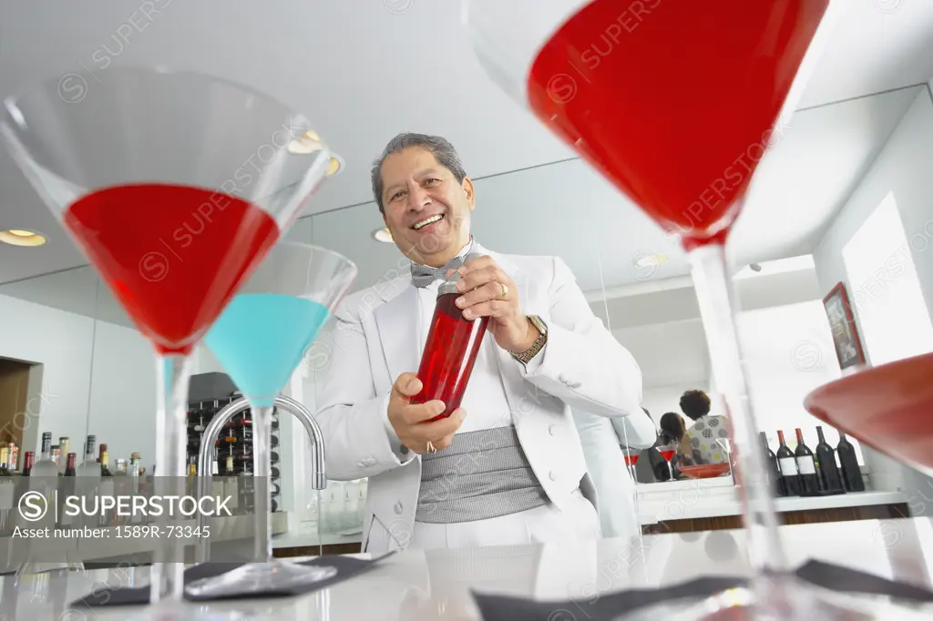 Hispanic host mixing martini cocktails at party