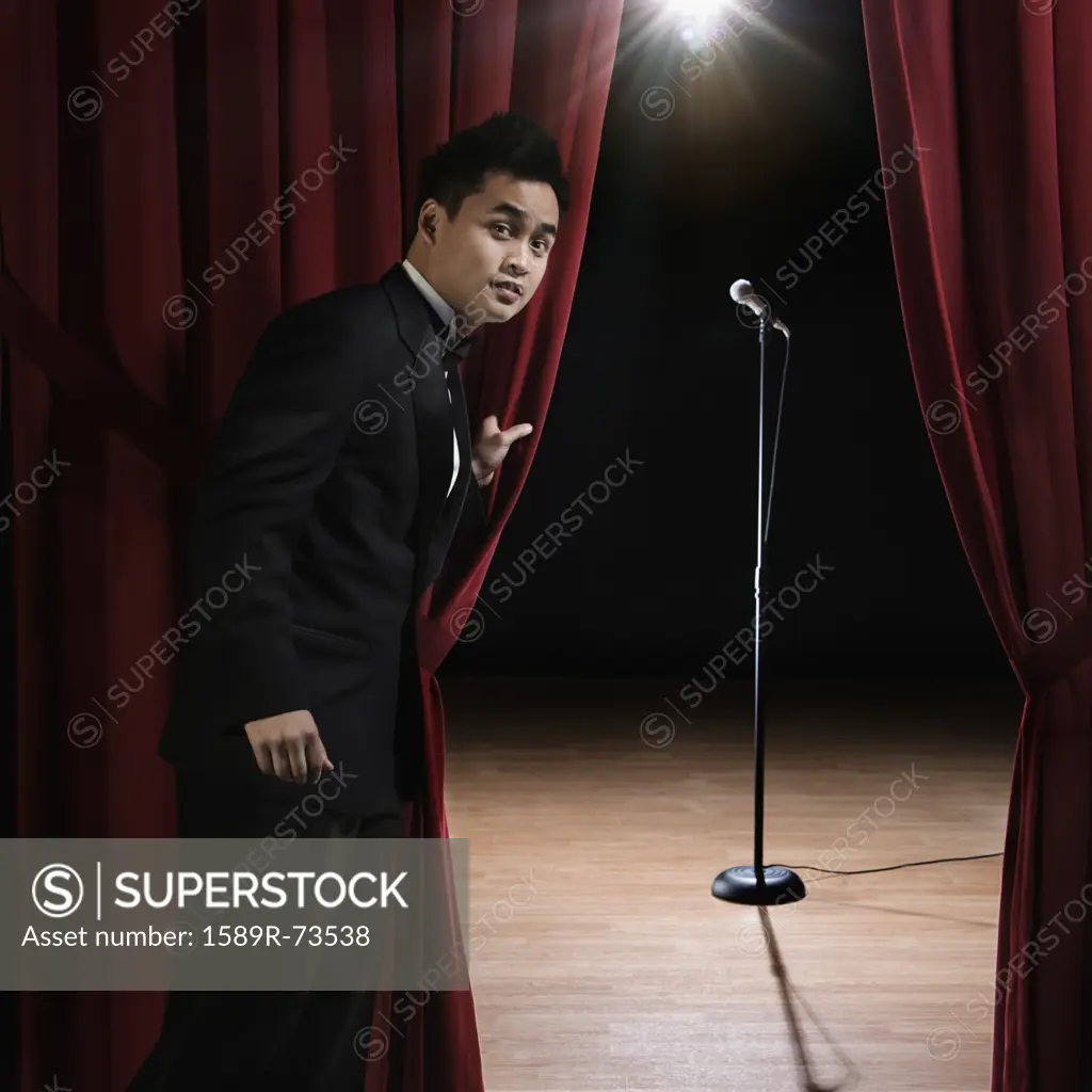 Asian man in tuxedo standing backstage