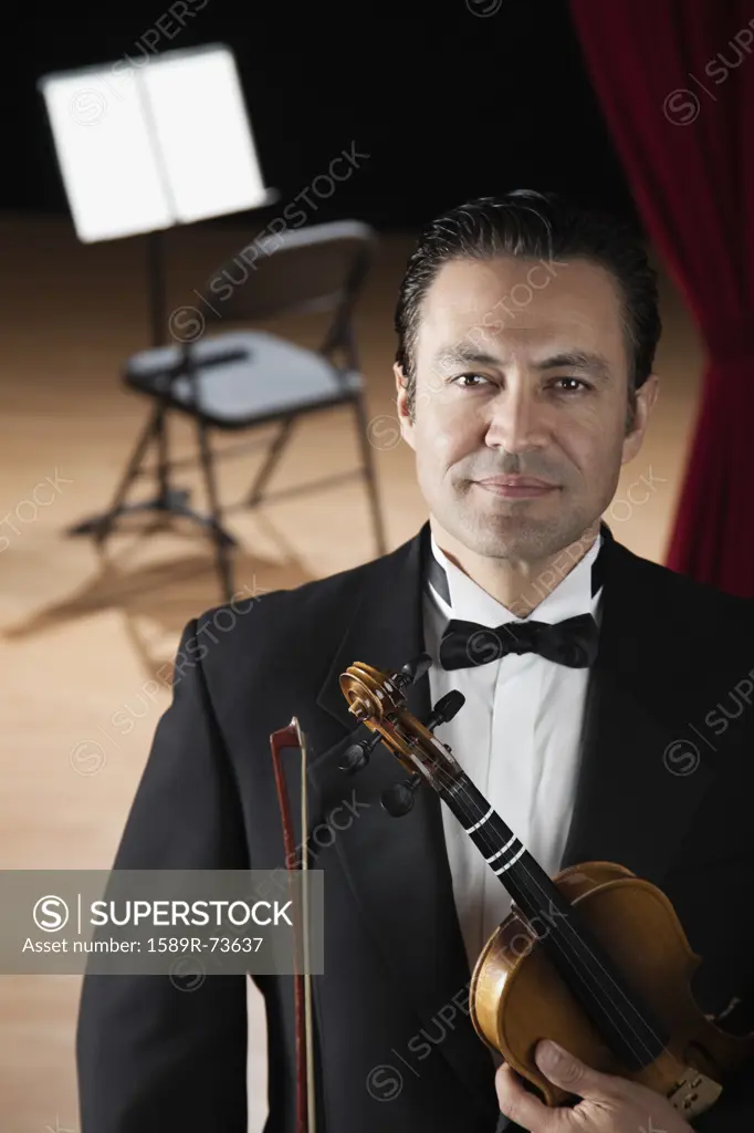 Hispanic man in tuxedo posing with violin