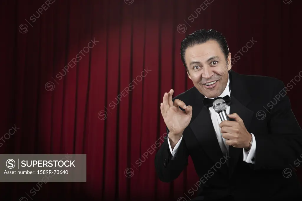 Hispanic man in tuxedo gesturing on stage