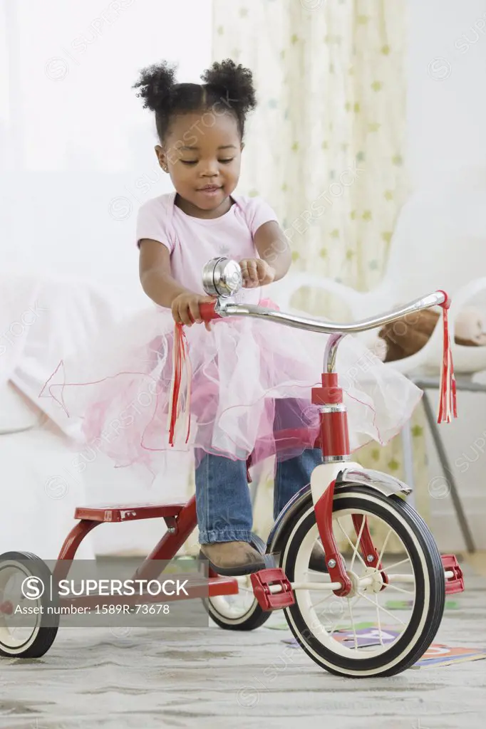 African American girl in costume riding tricycle