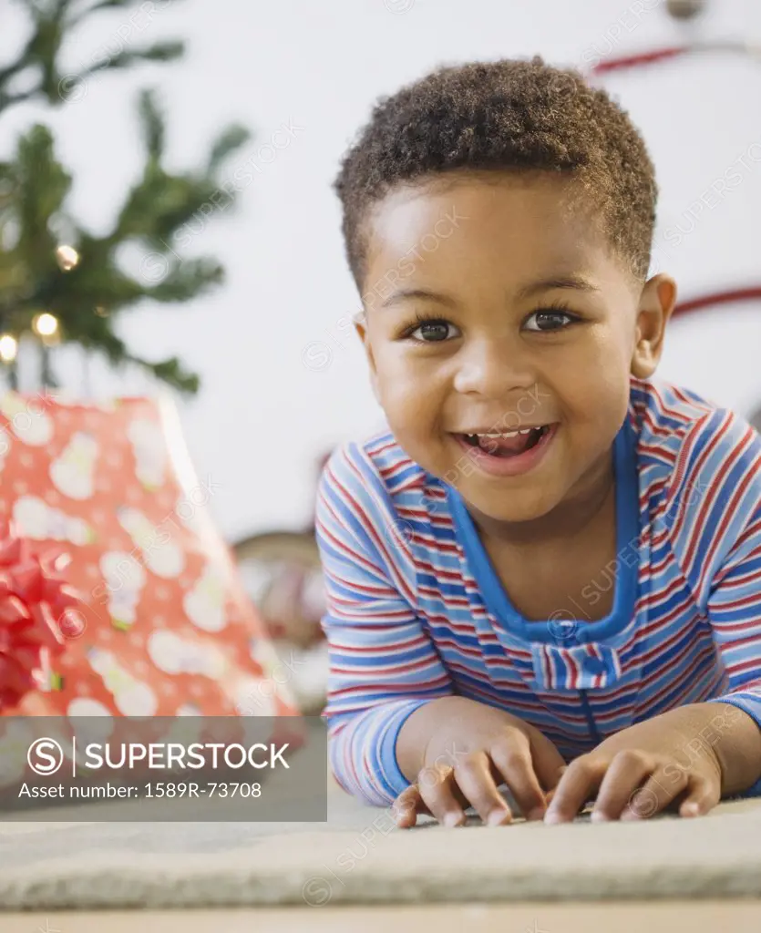 African American boy laying on floor by Christmas tree