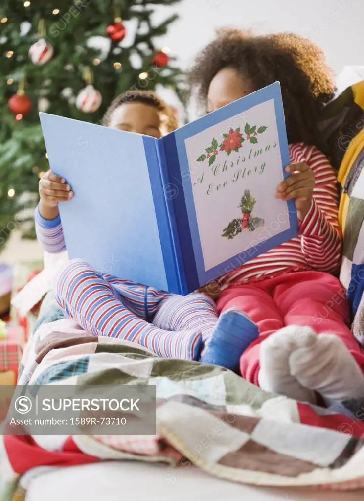African American brother and sister reading Christmas book