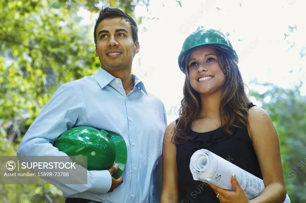 Hispanic business people with green hard hats