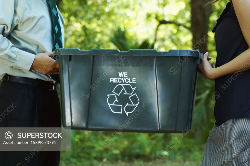 Hispanic business people carrying recycling bin