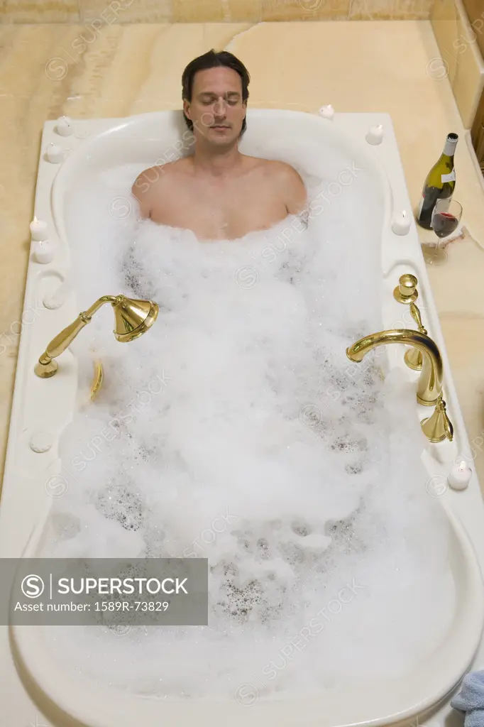 Hispanic man relaxing in bubble bath