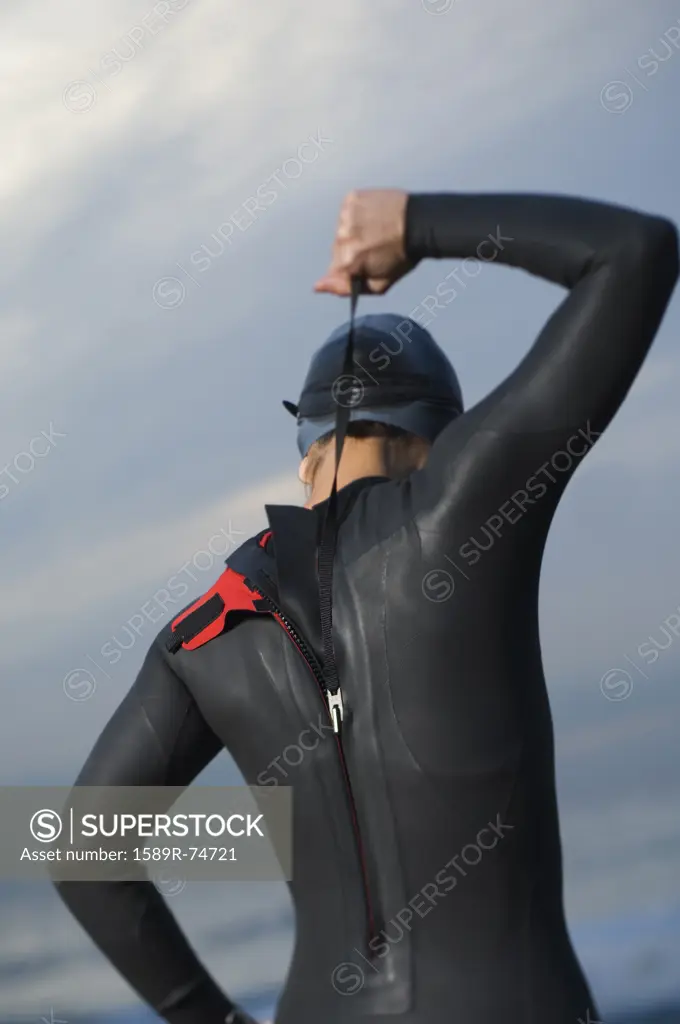 Hispanic woman zipping wetsuit on beach