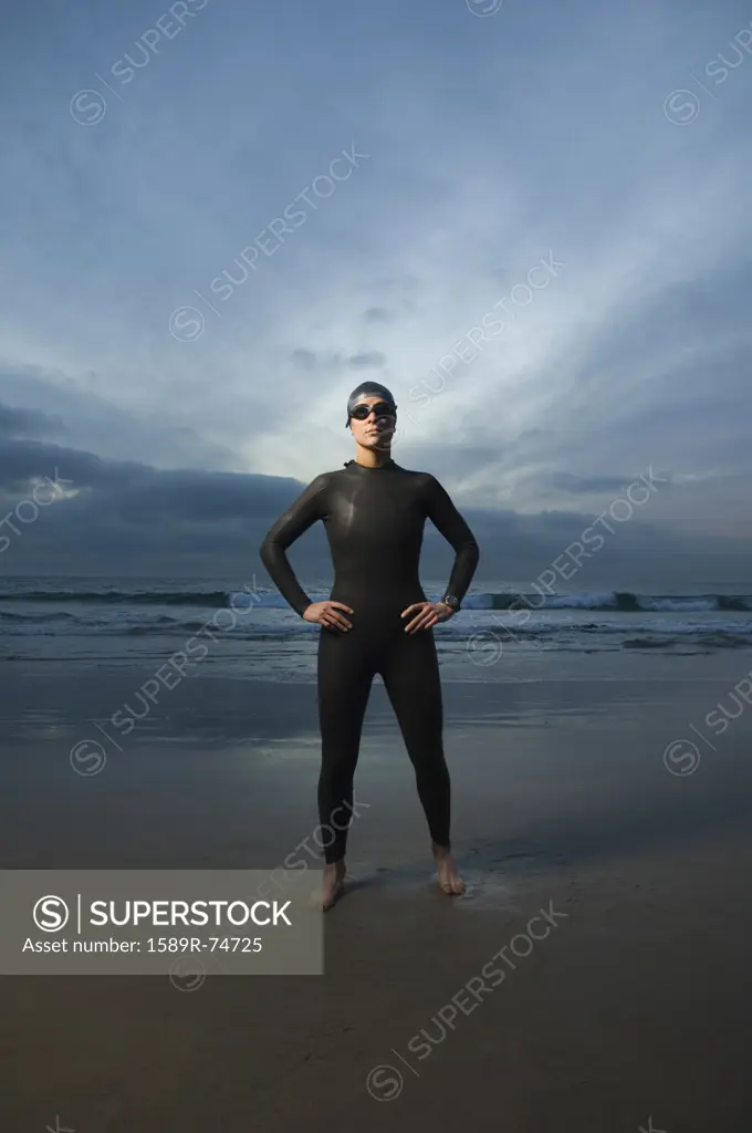 Hispanic woman in wetsuit on beach