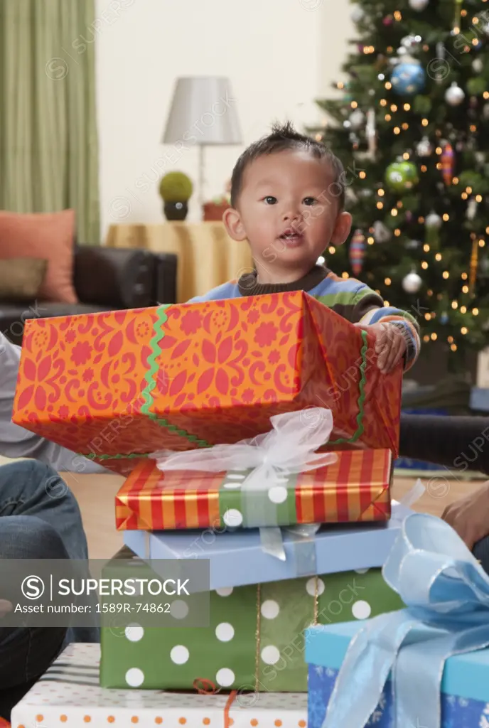 Asian boy opening Christmas gifts
