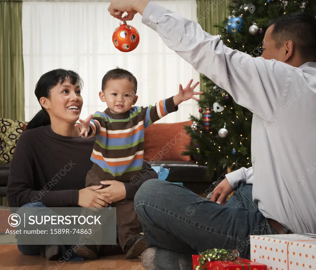 Asian family with ornament next to Christmas tree