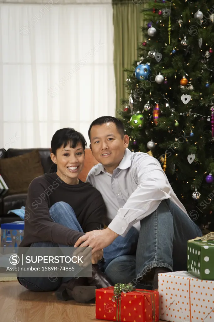 Asian couple next to Christmas tree