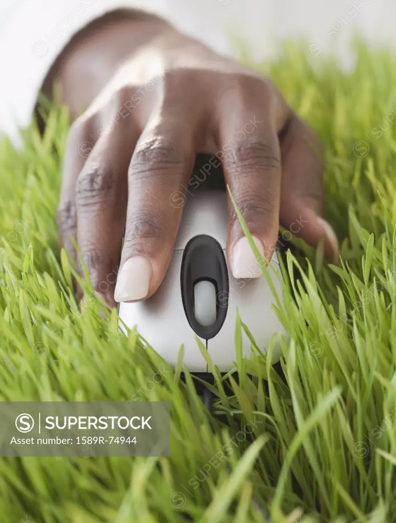 African woman using computer mouse in grass