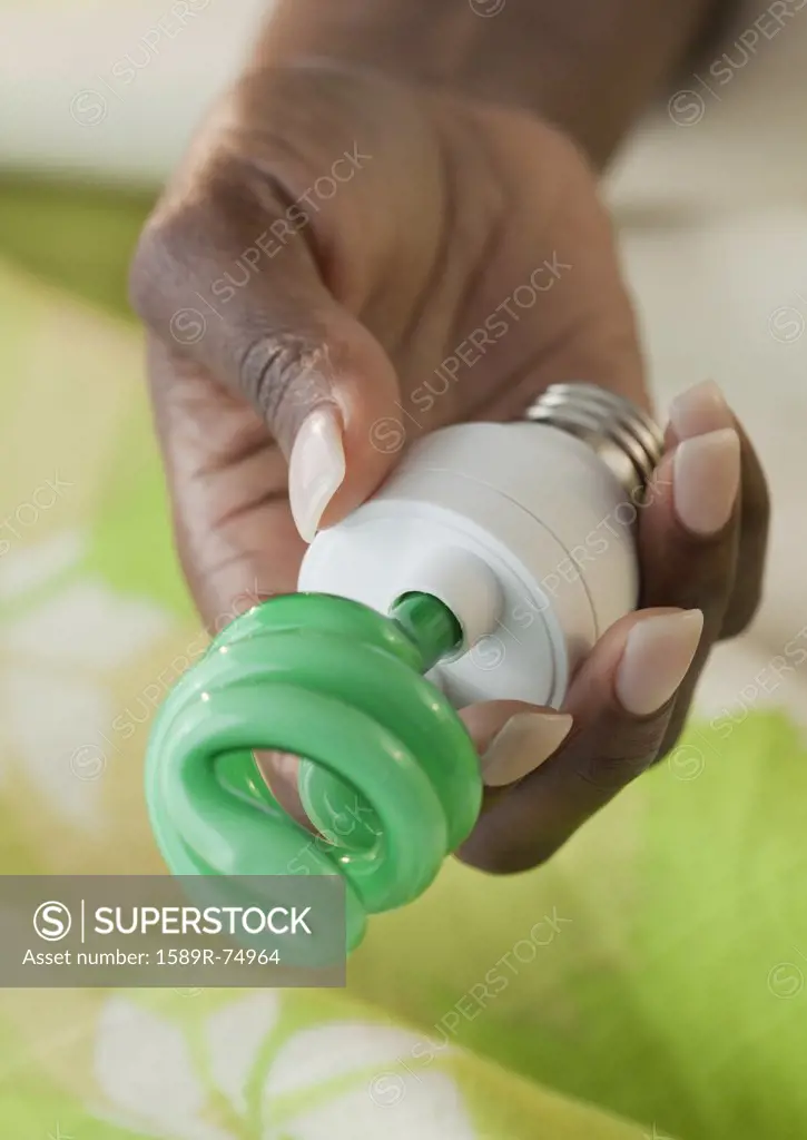 African woman holding CFL light bulb