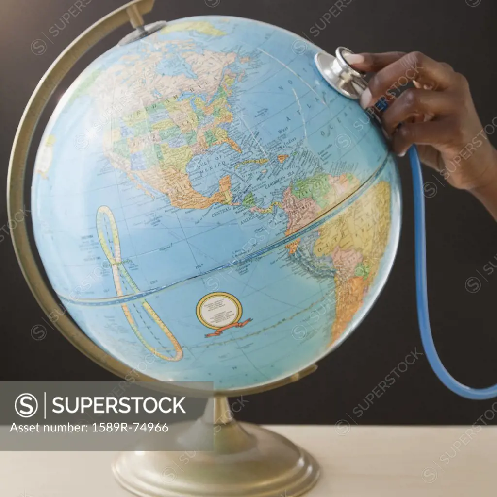 African woman using stethoscope on globe