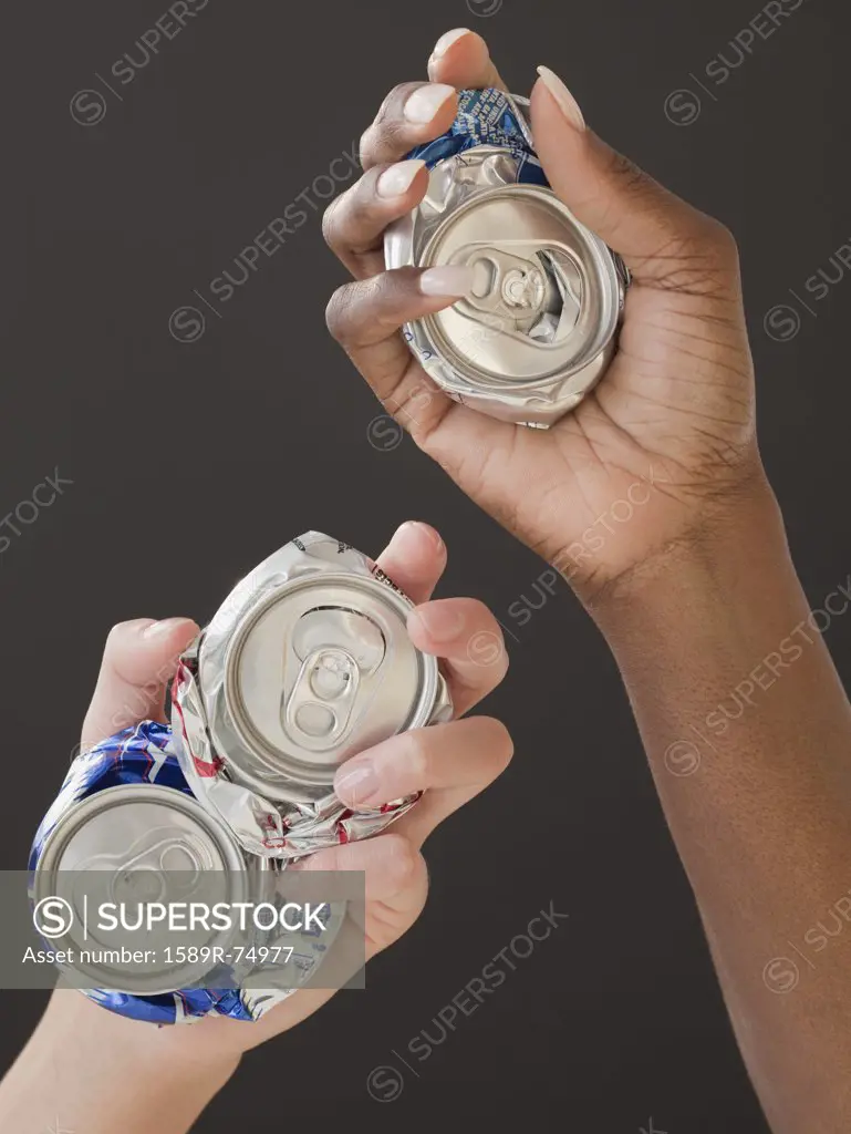 African and Caucasian woman holding crushed cans