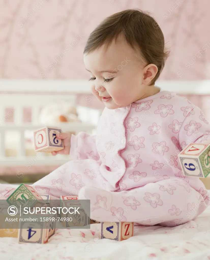 Mixed race baby girl playing with alphabet blocks