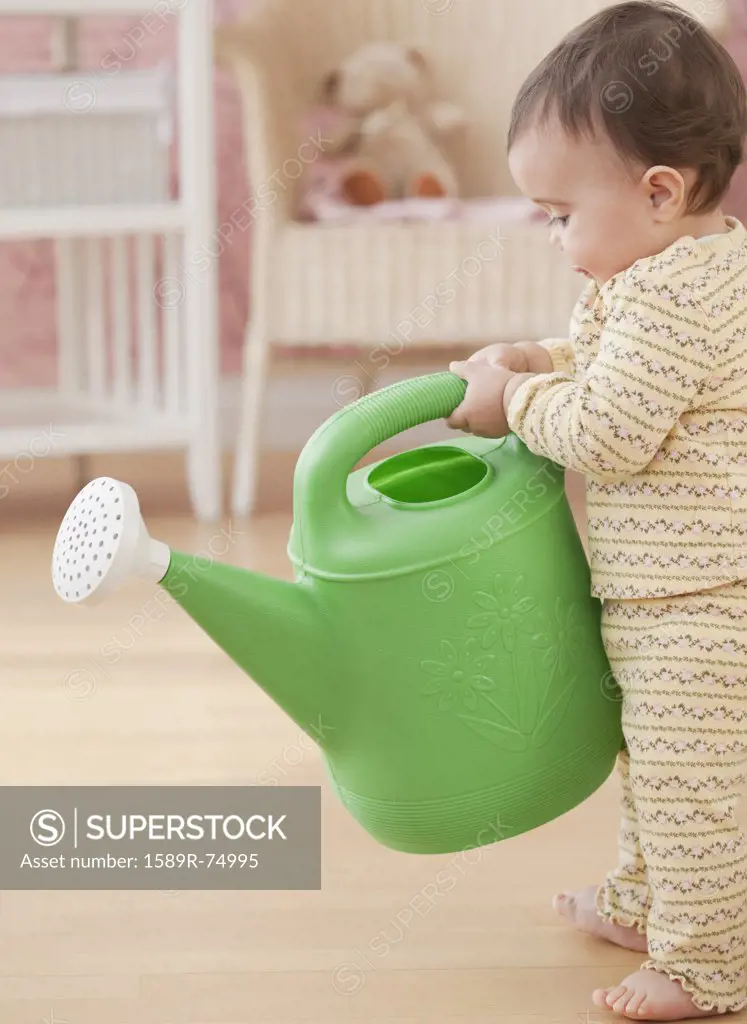 Mixed race baby girl holding watering can