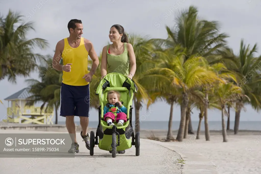 Hispanic couple pushing baby in jogging stroller