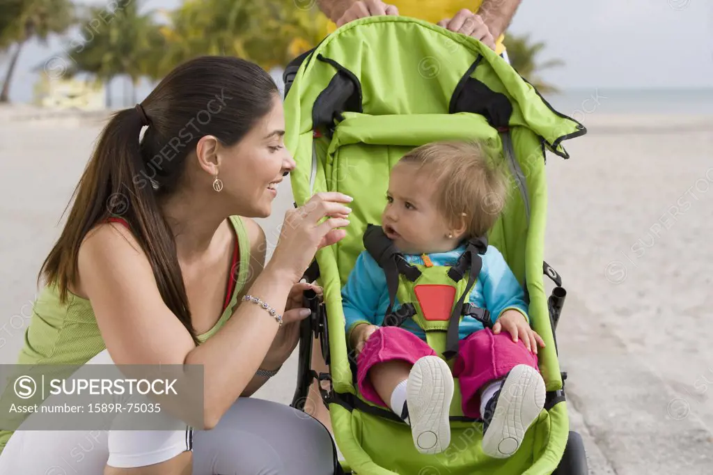 Hispanic woman checking on baby in jogging stroller