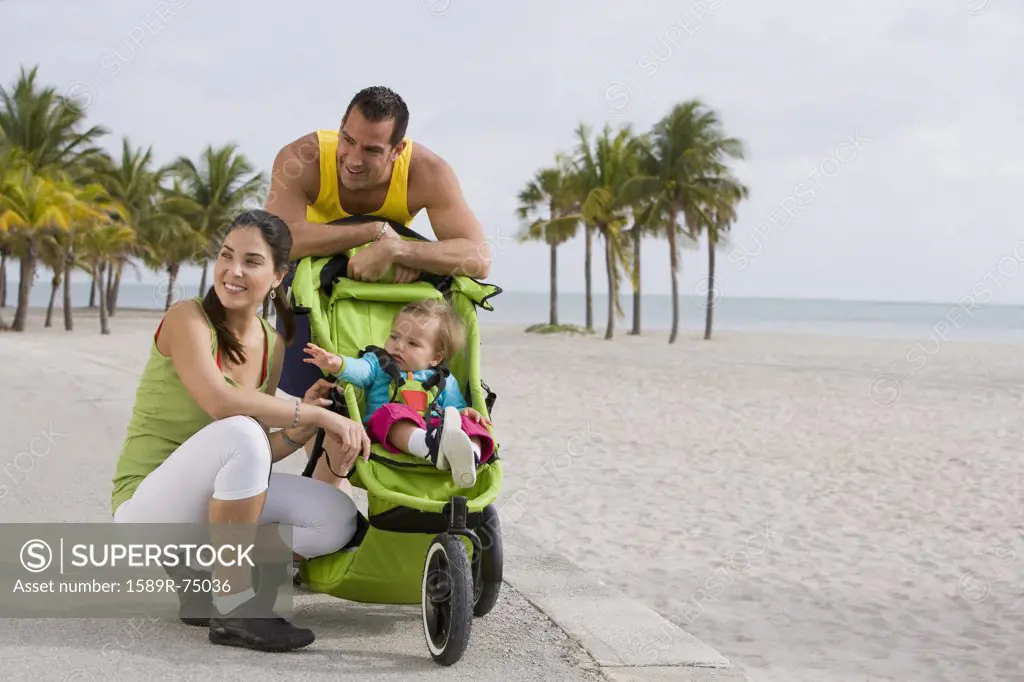 Hispanic couple stopping with baby in jogging stroller
