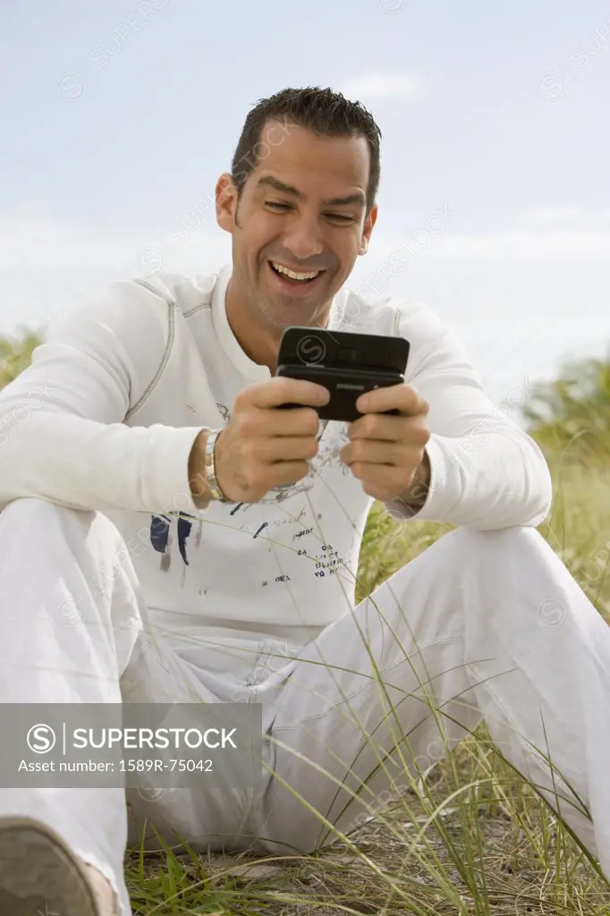 Hispanic man laughing at text message