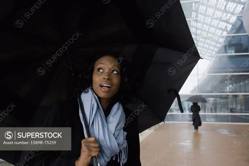 African businesswoman holding umbrella in rain