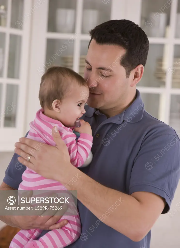 Hispanic father cuddling baby girl