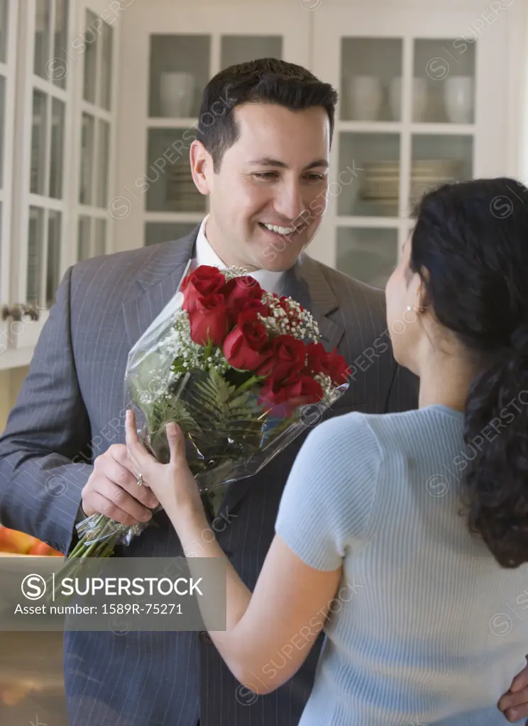 Hispanic man giving wife red roses