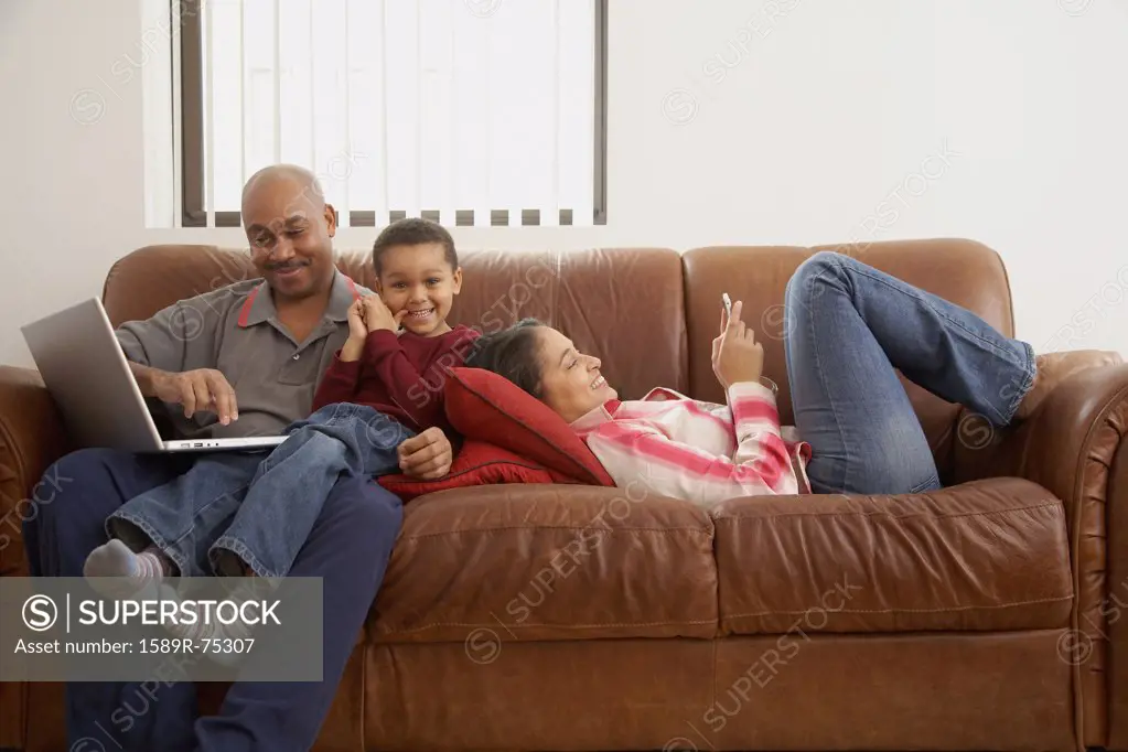 Antiguan man using laptop in living room with family