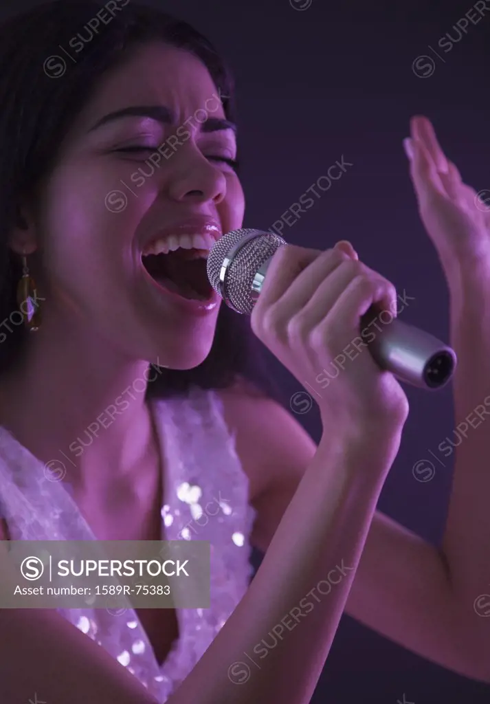 Hispanic woman singing into microphone