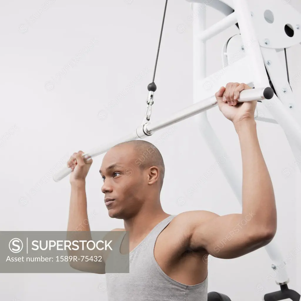 African man using weight machine in health club