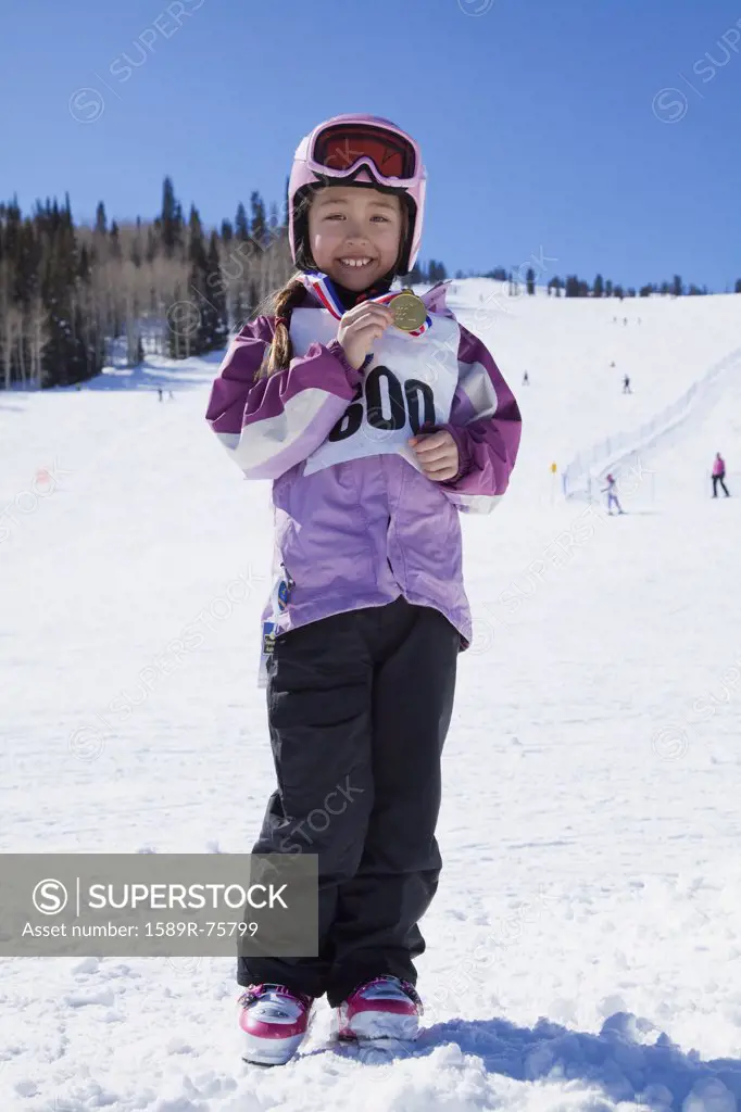 Mixed race girl showing off skiing medal