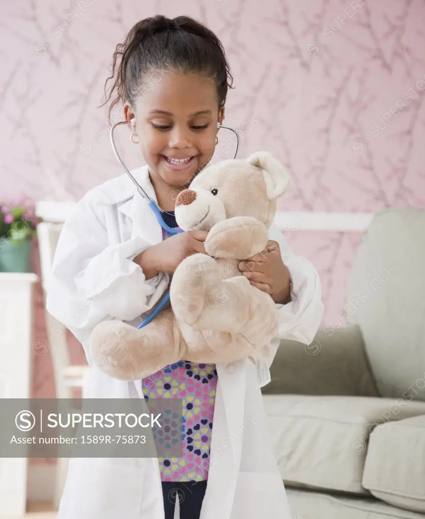 African girl playing doctor with teddy bear